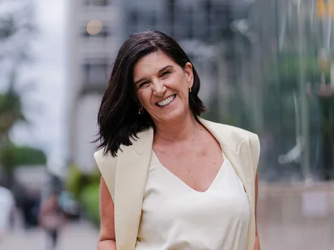 Illustrative photograph of a smiling woman in a cream suit on a city street