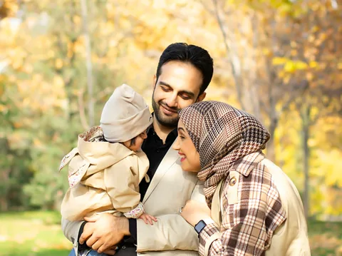 Illustrative photograph of a smiling family with a baby in an autumn park